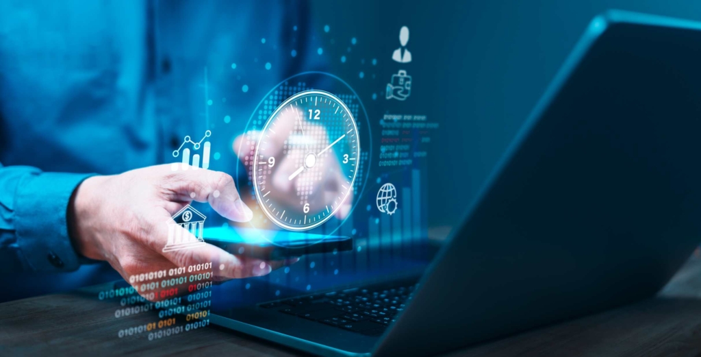 Enterprise Vulnerability Management. A hand interacts with a tablet in front of a laptop. The screen emits a glowing digital clock and data charts. It suggests time-sensitive data processing, real-time monitoring, or system uptime.